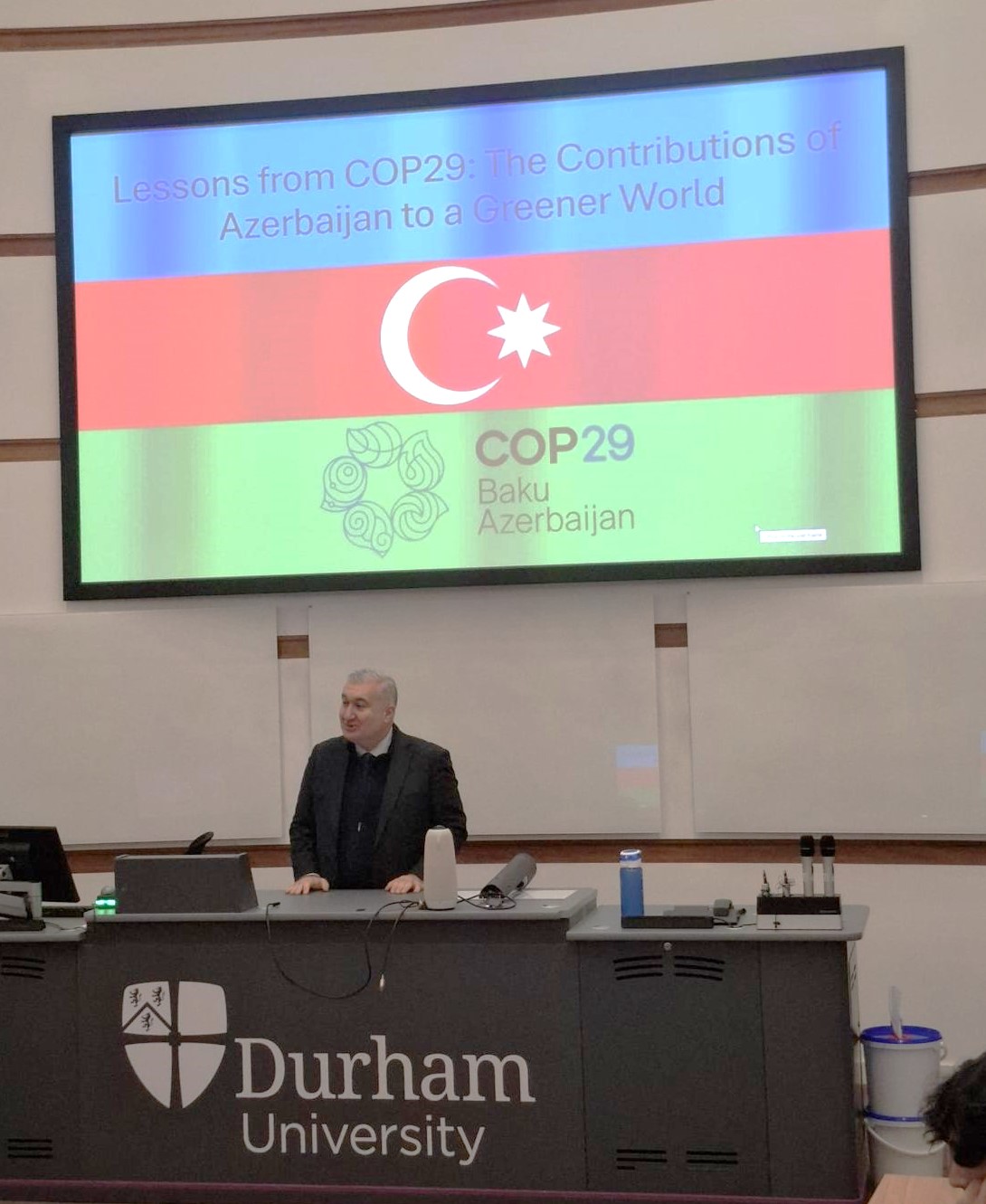 The Azerbaijani Ambassador standing in front of a PowerPoint presentation